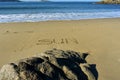 Beach with the word Ã¢â¬ÅsunÃ¢â¬Â written in the sand. Rocks and blue sea with foam, sunny day. Galicia, Spain. Royalty Free Stock Photo